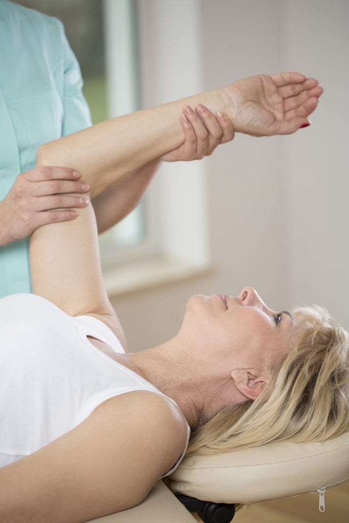 Elderly woman exercising at female physiotherapist's office